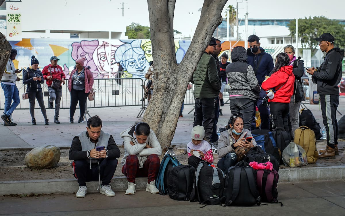 Migrantes deportados descansan en un anden en el puerto fronterizo de El Chaparral, este miércoles en Tijuana (México). //EFE