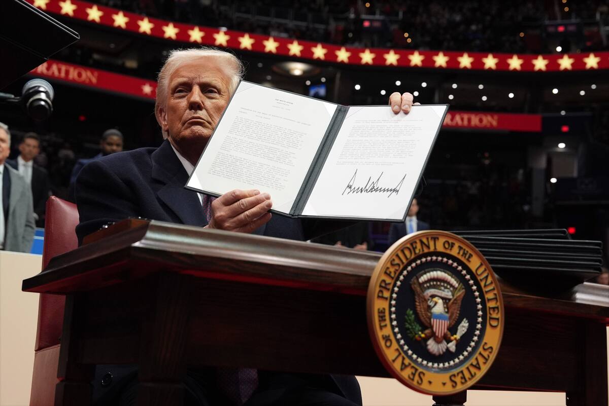 El presidente Donald Trump firma una orden ejecutiva durante un desfile bajo techo por la inauguración presidencial en el estadio Capital One. //AP