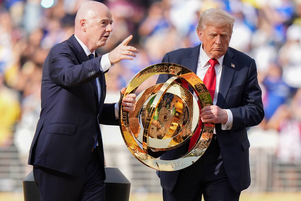 El presidente de la FIFA, Gianni Infantino (I), y el presidente Donald Trump llevan el trofeo del campeonato después de la final de la Copa Mundial de Clubes entre París Saint-Germain y Chelsea. //Foto, AP: Frank Franklin II