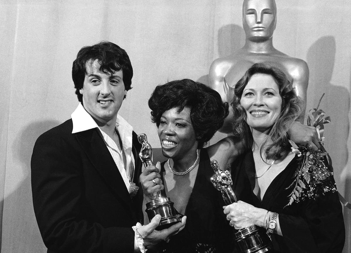 El actor y guionista Sylvester Stallone, a la izquierda, posa con Eletha Finch, al centro, viuda del actor Peter Finch, y la actriz Faye Dunaway en la ceremonia de los Premios Óscar, el 28 de marzo de 1977, en Los Ángeles. // (AP Foto/Archivo)