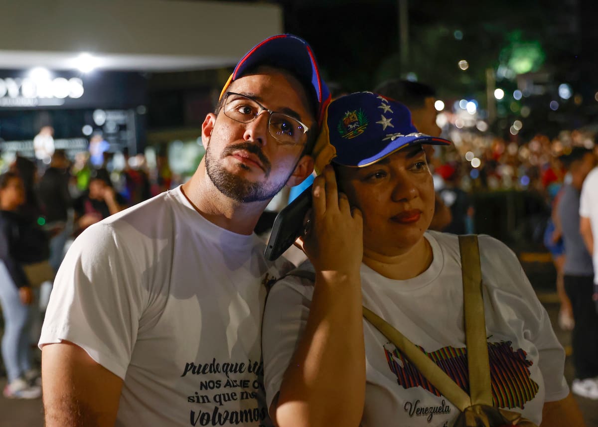 Dos ciudadanos venezolanos escuchan los resultados del primer boletín oficial de las elecciones presidenciales.