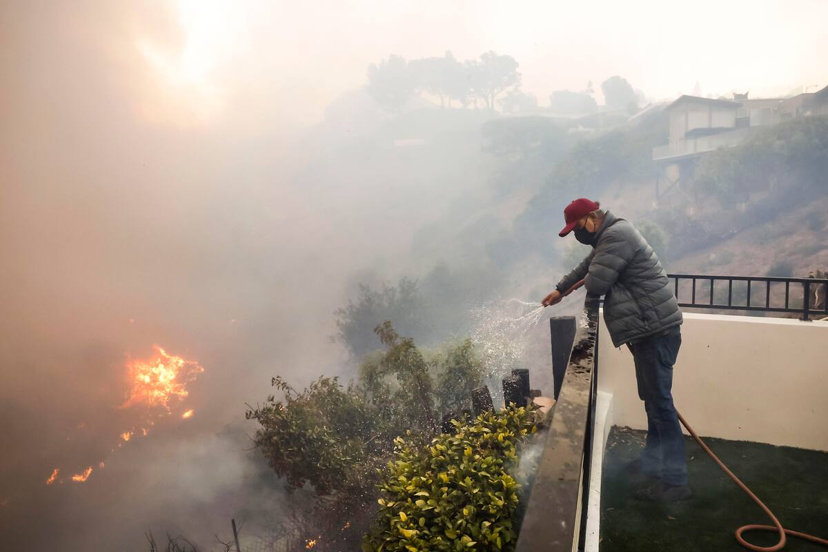 Los bomberos del condado de Los Ángeles utilizan mangueras y lanzan agua desde un helicóptero para combatir el incendio forestal de Palisades en Pacific Palisades, California, (EE.UU.). EFE/CAROLINE BREHMAN