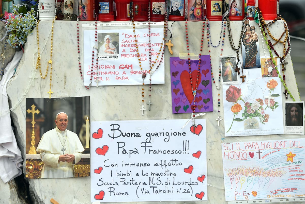 Velas, rosarios y mensajes de apoyo al papa Francisco se exhiben en la estatua del papa Juan Pablo II junto al Hospital Universitario Gemelli, donde está hospitalizado, en Roma. //EFE