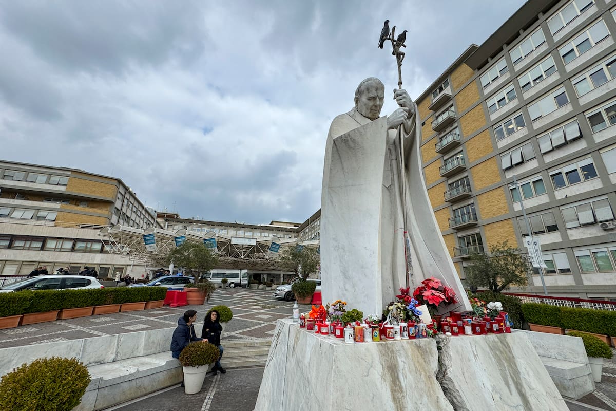 Velas y flores a los pies de la escultura de Juan Pablo II a las puertas del Hospital Gemelli de Roma donde permanece ingresado el papa Francisco. //EFE
