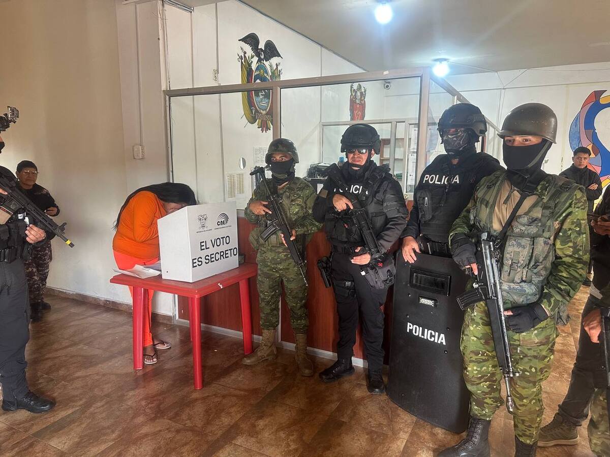 Un grupo de policías custodia a una mujer mientras vota, durante el inicio de los comicios generales en Ecuador. //EFE