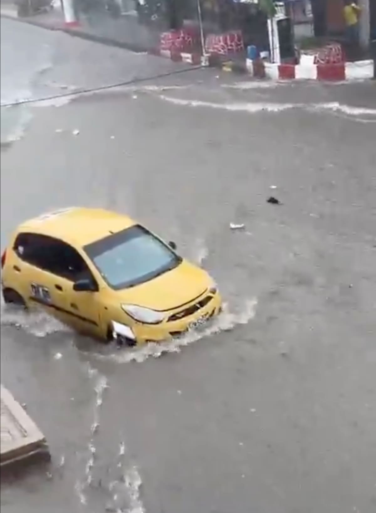 En la carrera 40 con calle 42, en el Centro de Barranquilla, un taxi tuvo que ser rescatado por dos hombres cuando era arrastrado por el arroyo.//Captura de pantalla.