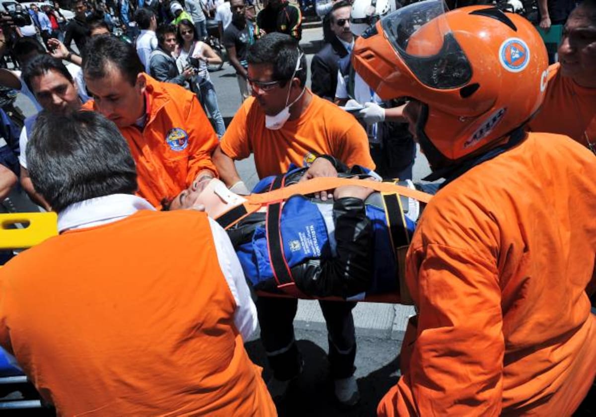 Emergency personnel assist an injured person on May 15, 2012 after an explosion ripped through a crowded area of Bogota injuring at least 10 people according to the mayor's office. Witnesses said the blast appeared to have been from a bomb placed on a public bus, but officials could not immediately confirm the cause. The explosion came shortly after police said they had dismantled a car bomb that leftist rebels allegedly planned to use in an attack on the city's police headquarters. AFP PHOTO/Guillermo LEGARIA