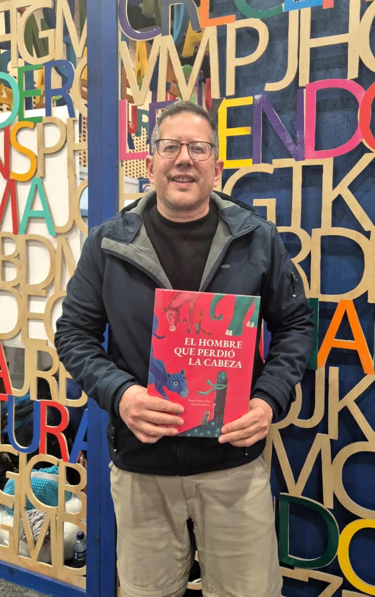 Fanuel Hanán Díaz junto a la portada de su libro “El hombre que perdió la cabeza”, un cuento singular que enriquece la literatura para niños y jóvenes. //Foto: Cortesía.