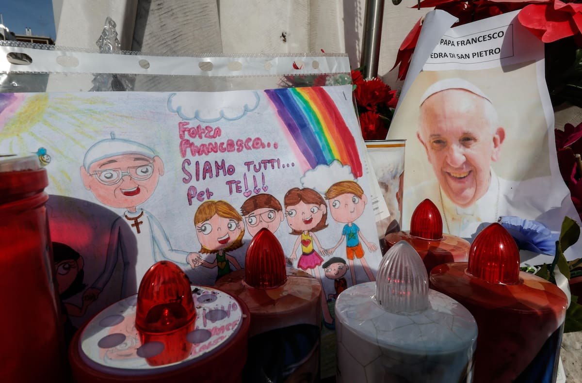 Un dibujo y una fotografía del papa Francisco bajo la estatua de Juan Pablo II, frente al Hospital Agostino Gemelli. //EFE