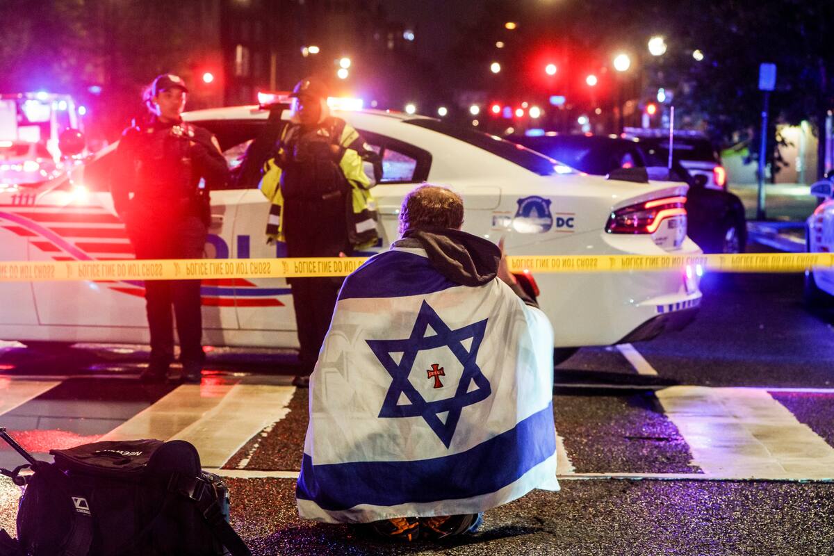 Un hombre con una bandera israelí en el lugar donde fueron asesinadas dos personas que trabajaban en la embajada de Israel en Washington. // Foto: EFE