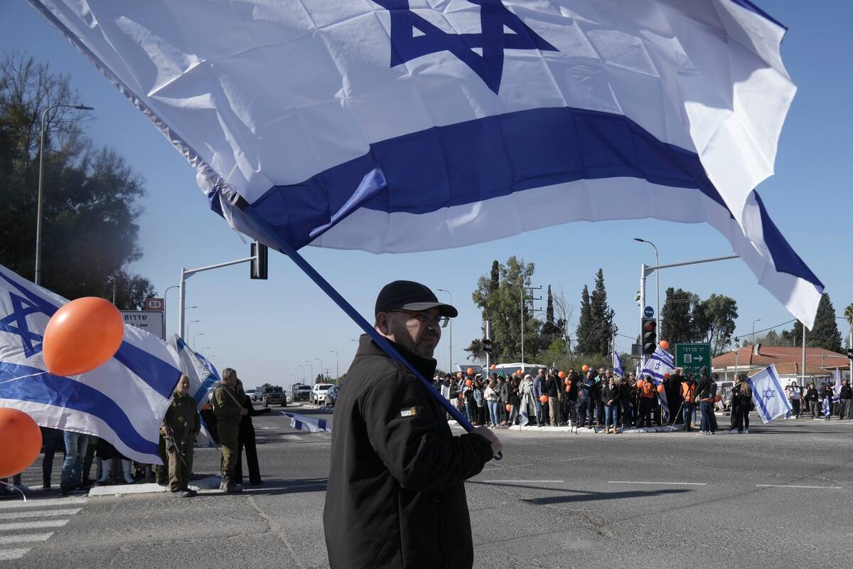 Israelíes esperan en la carretera el paso de la comitiva fúnebre de Shiri Bibas y sus dos hijos, Ariel and Kfir, que murieron durante su cautiverio en Gaza, cerca del kibbutz Yad Mordechai, en Israel. //AP