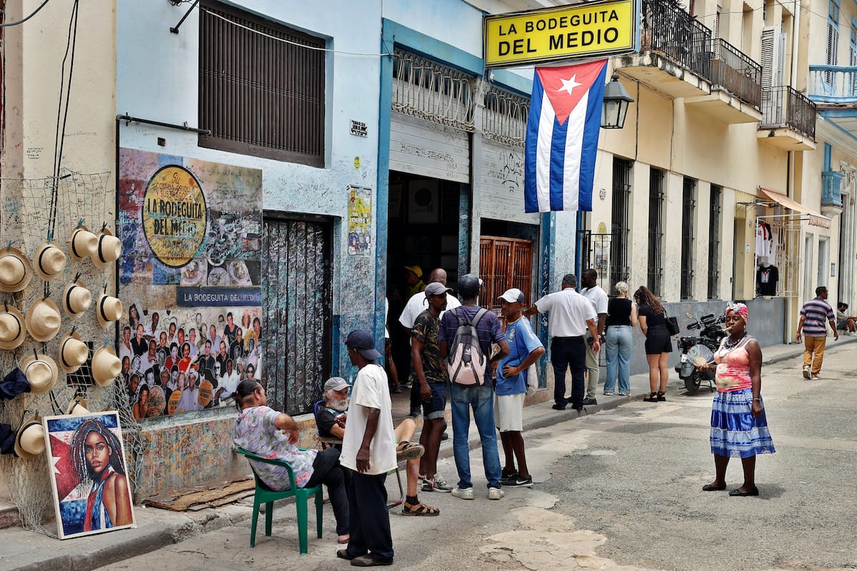 Personas conversan frente al restaurante y bar La Bodeguita del Medio este martes, en La Habana (Cuba). La grave crisis económica cubana y el miedo a las sanciones de EE.UU. están terminando de desarbolar el sector turístico de la isla, antes motor clave de su crecimiento, con la salida parcial o total de las cuatro grandes hoteleras del país en una semana. EFE/ Ernesto Mastrascusa