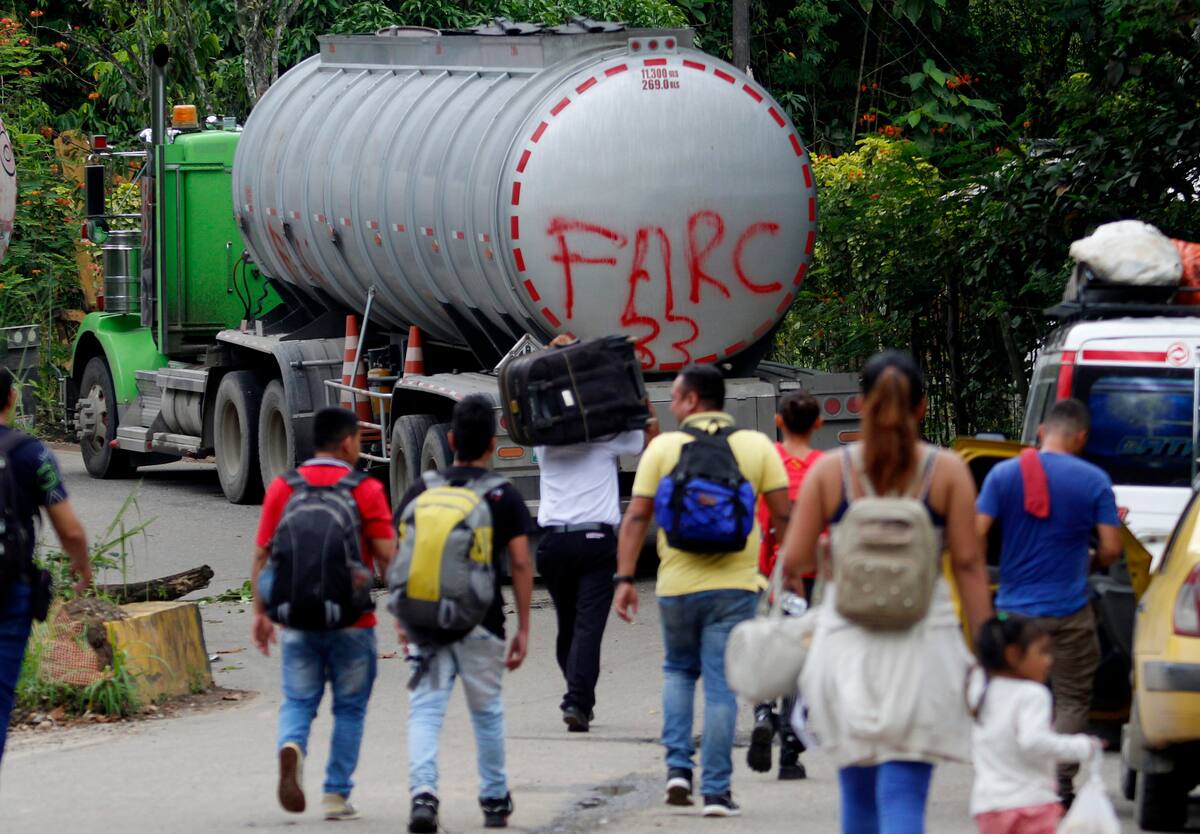 Fotografía de archivo del 16 de agosto de 2023 de personas caminando junto a un camión con la frase "FARC 33" en la Vereda Santa Rosa, en Catatumbo. // Foto: EFE