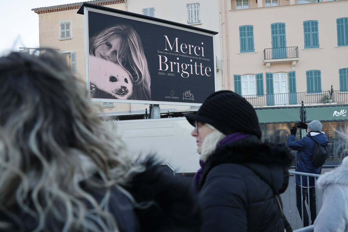 Un admirador toma una fotografía de una foto impresa de Brigitte Bardot poco antes del servicio funerario. //Foto: EFE.