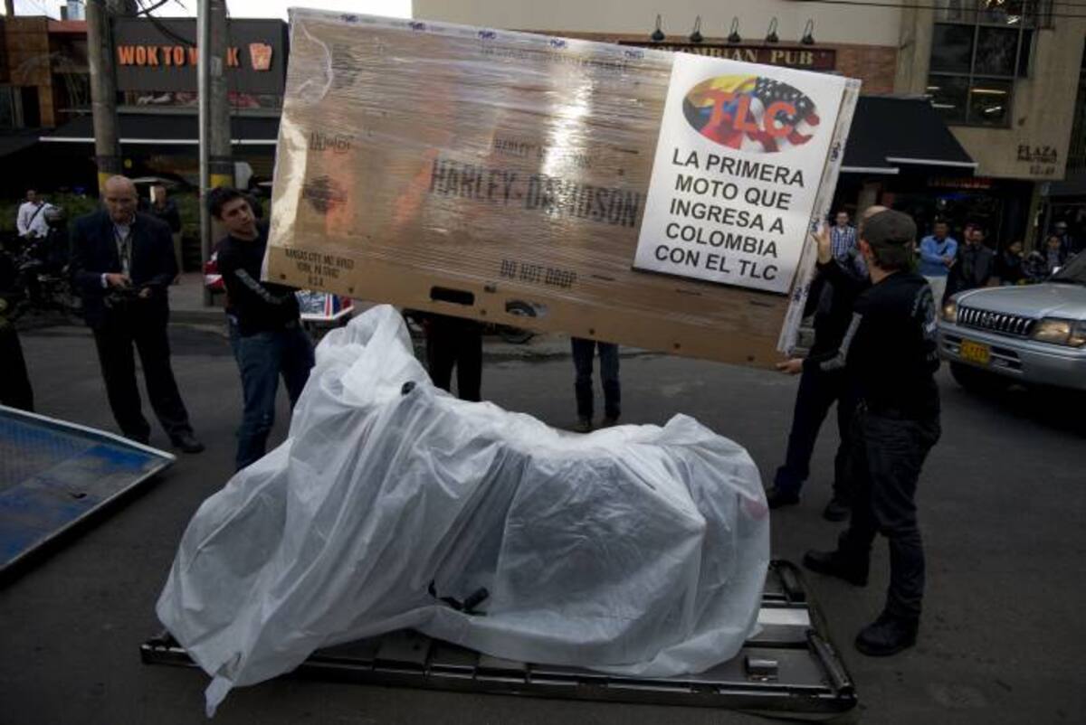 Trabajadores cargan un pancarta para anunciar la llegada de la primera moto cobijada por el TLC. AFP EITAN ABRAMOVICH
