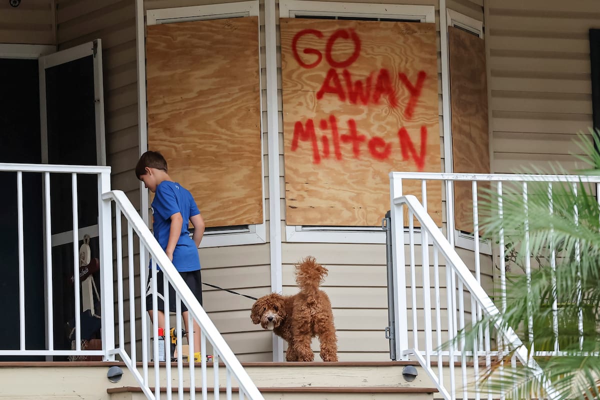 Noah Weibel y su perro, Cookie, suben las escaleras de su casa mientras su familia se prepara para la llegada del huracán Milton. //AP