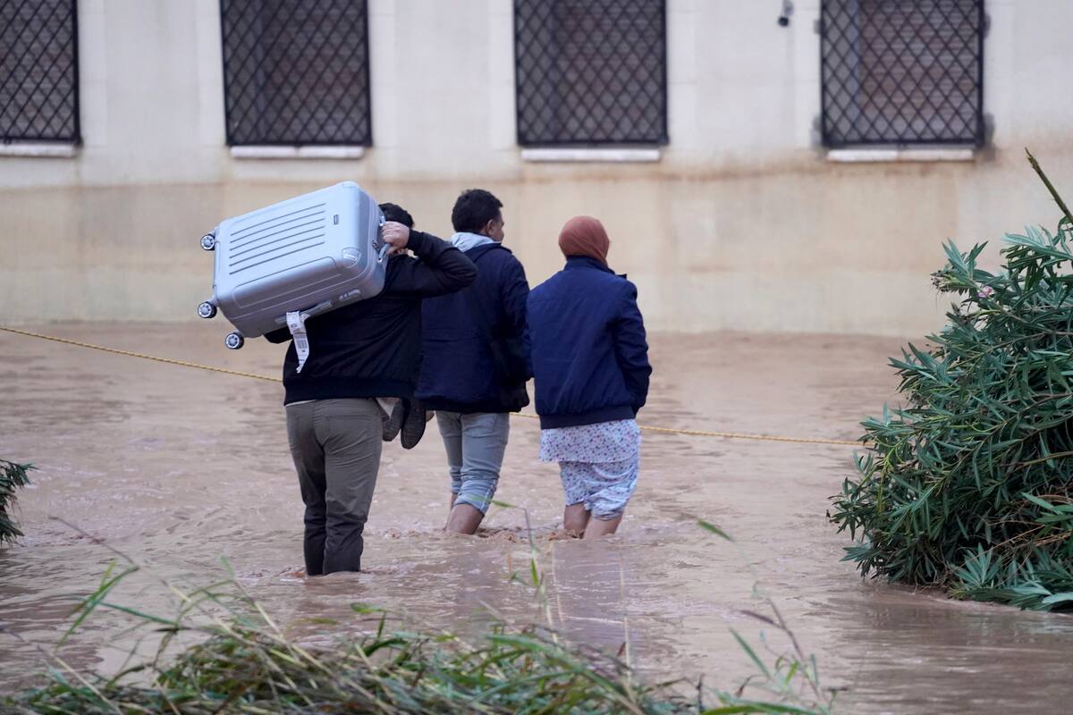 Varias personas, algunos con pertenencias, caminan por calles inundadas en Valencia, el miércoles 30 de octubre de 2024. //AP