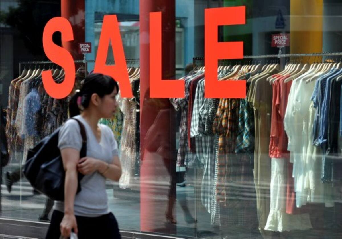 Pedestrian walks in front of a boutique advertising a sale in Tokyo's Shinjuku shopping district on August 16, 2010. Japan's economy grew at a much weaker than expected pace and was overshadowed by China in the second quarter, data showed, amid further signs the global recovery is losing steam. AFP PHOTO/Kazuhiro NOGI