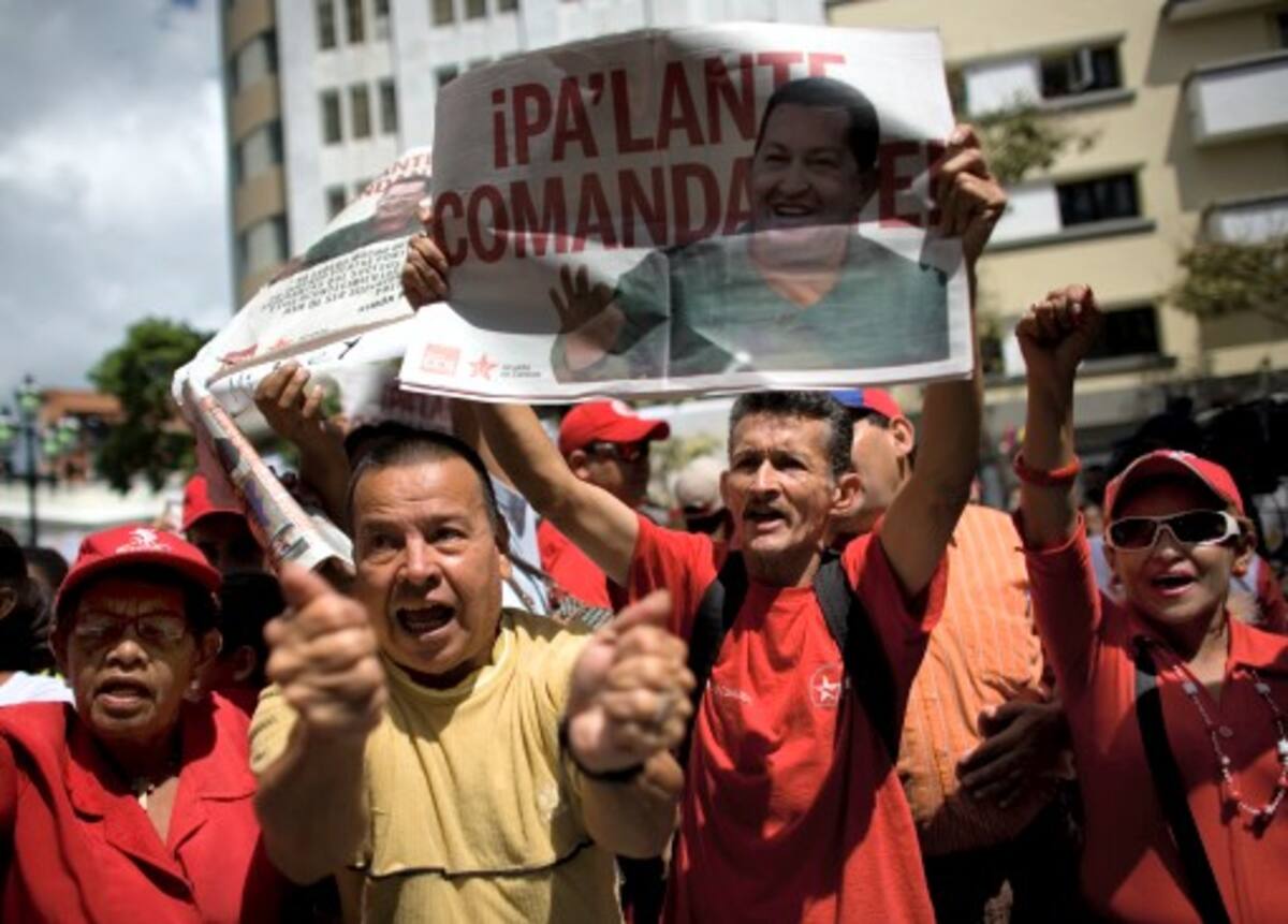 El jefe de Estado apareció sonriente, vestido de militar y boina roja y ondeando una bandera venezolana ante una multitud enfervorizada que entonó junto a él el himno nacional. AP Ariana Cubillos