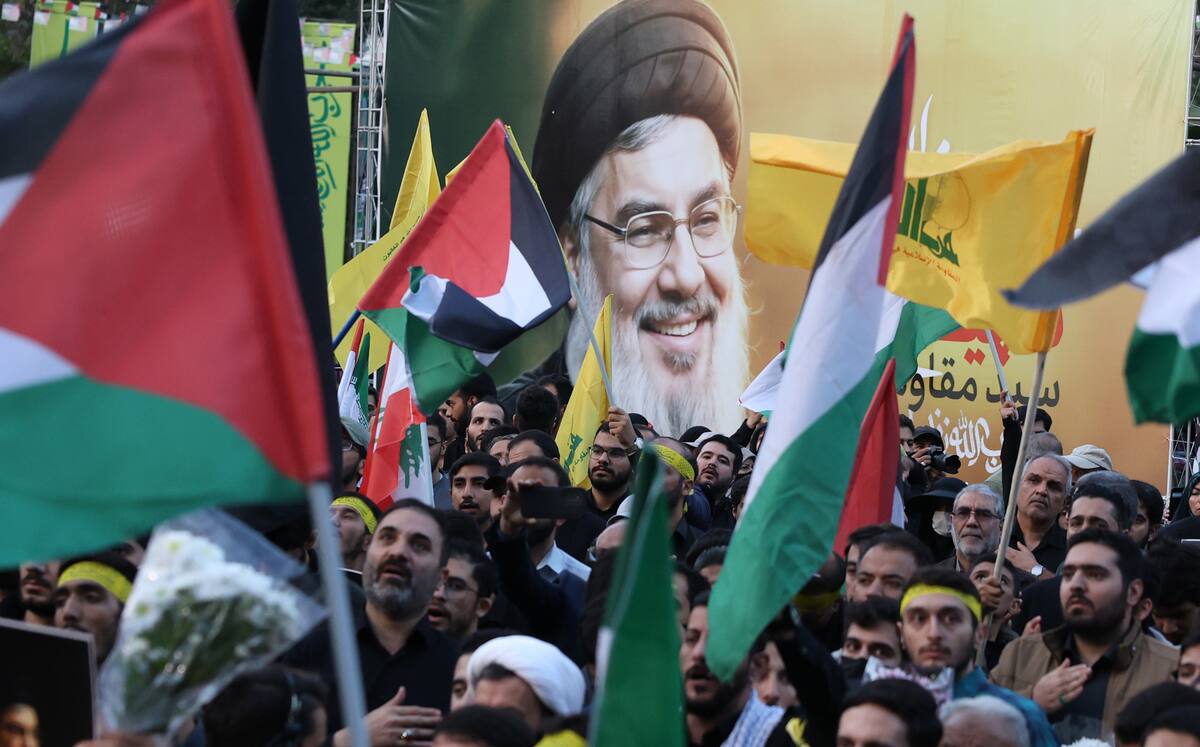 Iraníes sostienen banderas palestinas junto a la foto del difunto líder de Hezbollah, Hassan Nasrallah. // EFE.