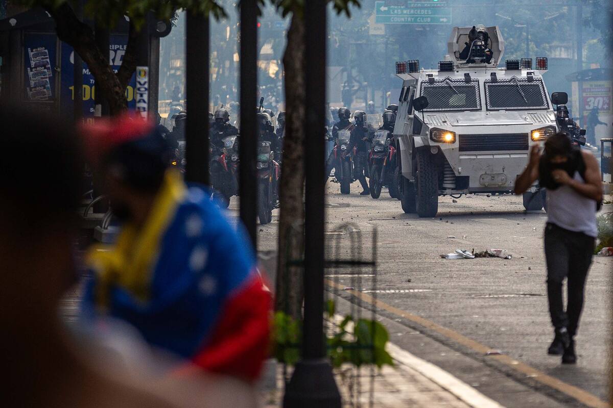 Manifestantes corren durante enfrentamientos entre opositores y miembros de la Guardia Nacional Bolivariana (GNB). //EFE