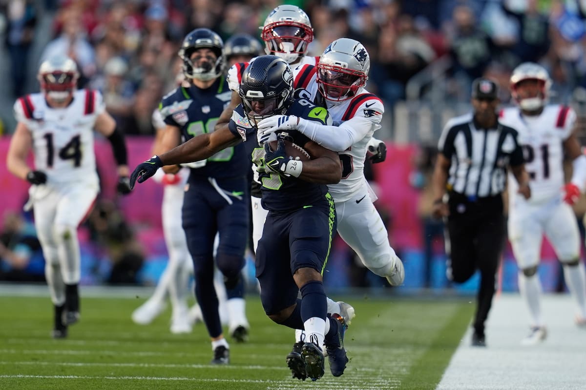 El corredor de los Seattle Seahawks, Kenneth Walker III, en el centro, es tackleado por el esquinero de los New England Patriots, Marcus Jones, durante la primera mitad del partido de fútbol americano Super Bowl 60 de la NFL. //Foto, AP: Steve Luciano