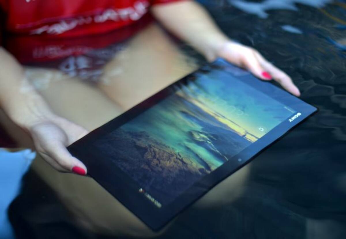 Un modelo sostiene última tablet resistente al agua de Sony mientras opera bajo el agua en el distrito central de negocios de Sydney. AFP SAEED KHAN