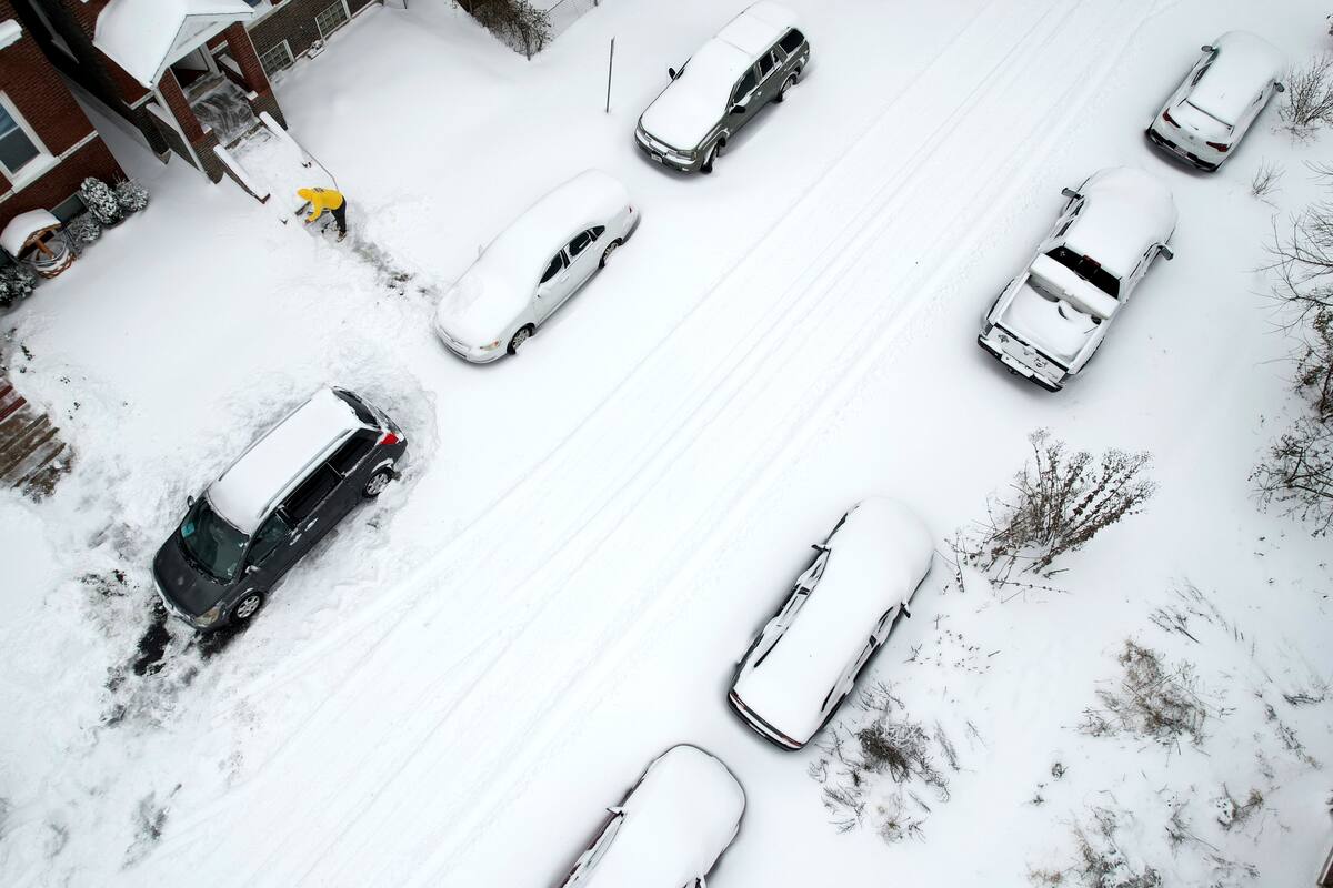 Una persona limpia la nieve de las escaleras delanteras de una casa después de una tormenta invernal. //AP