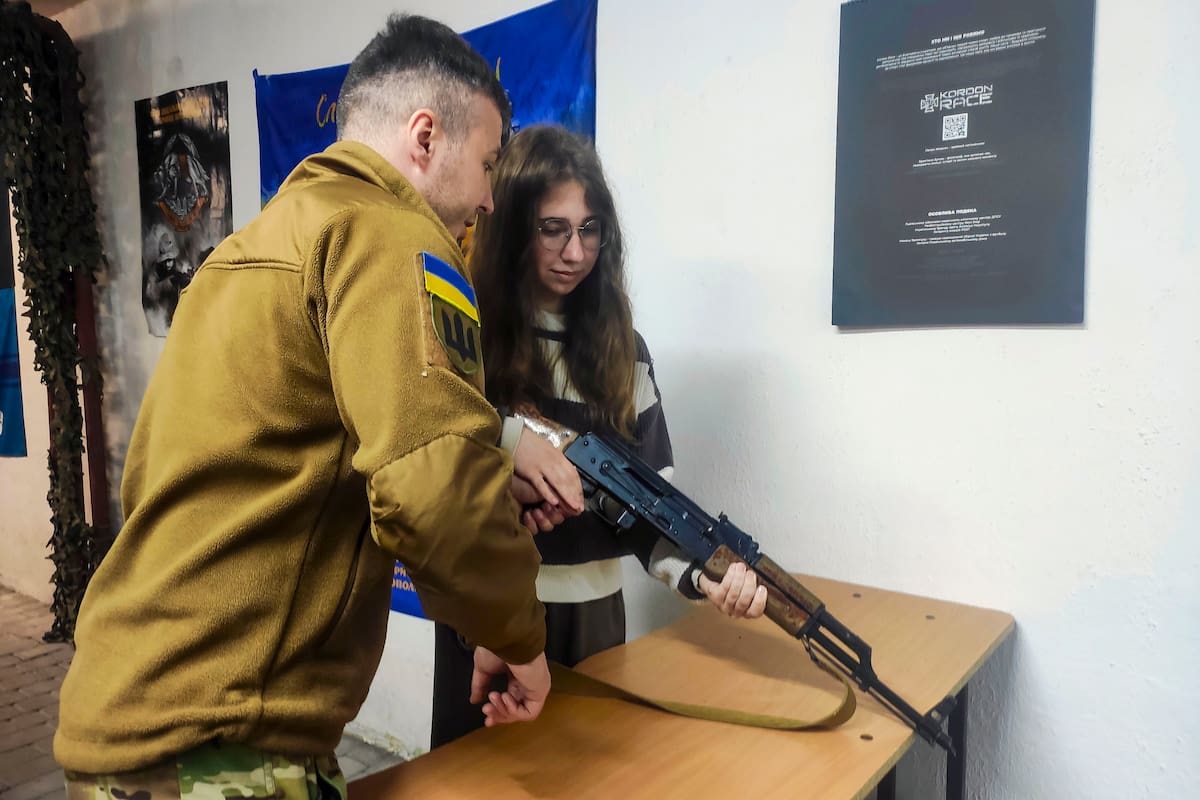 El instructor Yaroslav (i) ayuda a Anna, de 16 años, a aprender a montar una réplica de rifle durante una clase de entrenamiento militar este jueves, en Leópolis (Ucrania). EFE/ Rostyslav Averchuk