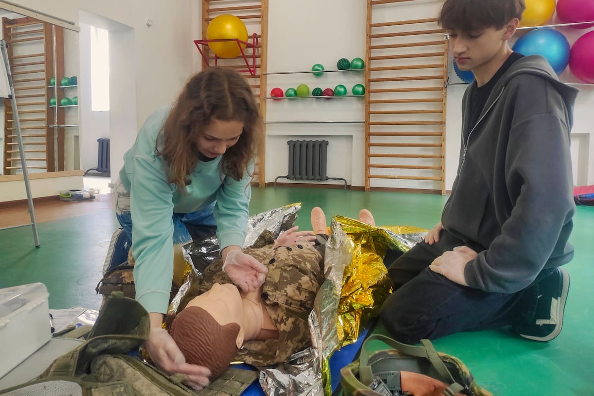 Estudiantes ucranianos aprenden de instructores militares experimentados cómo detener una hemorragia grave en combate o tras un ataque aéreo ruso este jueves, en Leópolis (Ucrania). //EFE - Rostyslav Averchuk.