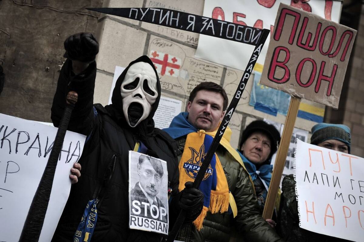 Personas sostenen una foto del presidente ruso Vladirmir Putin caricaturizado como Adolf Hitler, en una manifestación para protestar por la postura de Rusia en la crisis de Ucrania AFP LOUISA GOULIAMAKI