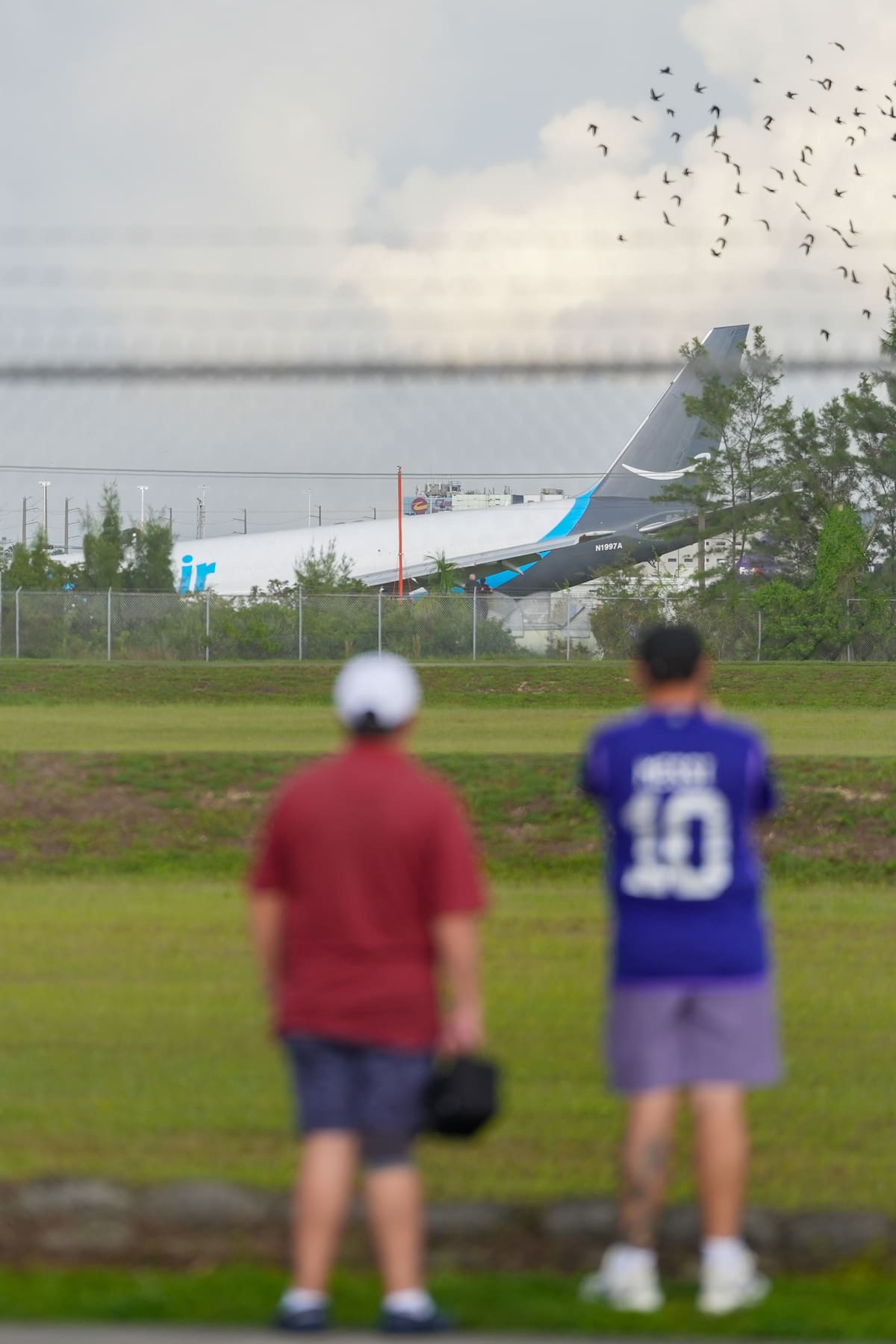 Personas observan un avión de carga con el logotipo de Amazon este domingo, en el Aeropuerto Internacional de Miami (EE.UU.). Un avión de carga con el logotipo de Amazon se estrelló al salirse de la pista después de aterrizar en el aeropuerto según informó la Administración Federal de Aviación (FAA, por sus siglas en inglés). // Foto: EFE/ Alberto Boal.