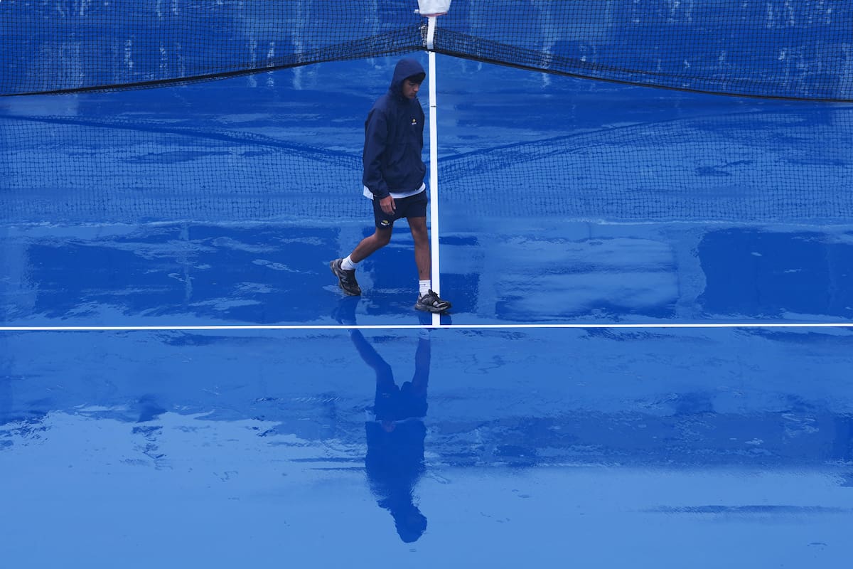 Un miembro del personal camina por la pista del estadio Grandstand durante una interrupción por lluvia en el torneo de tenis del Abierto de Estados Unidos. //Foto, AP: Kirsty Wigglesworth