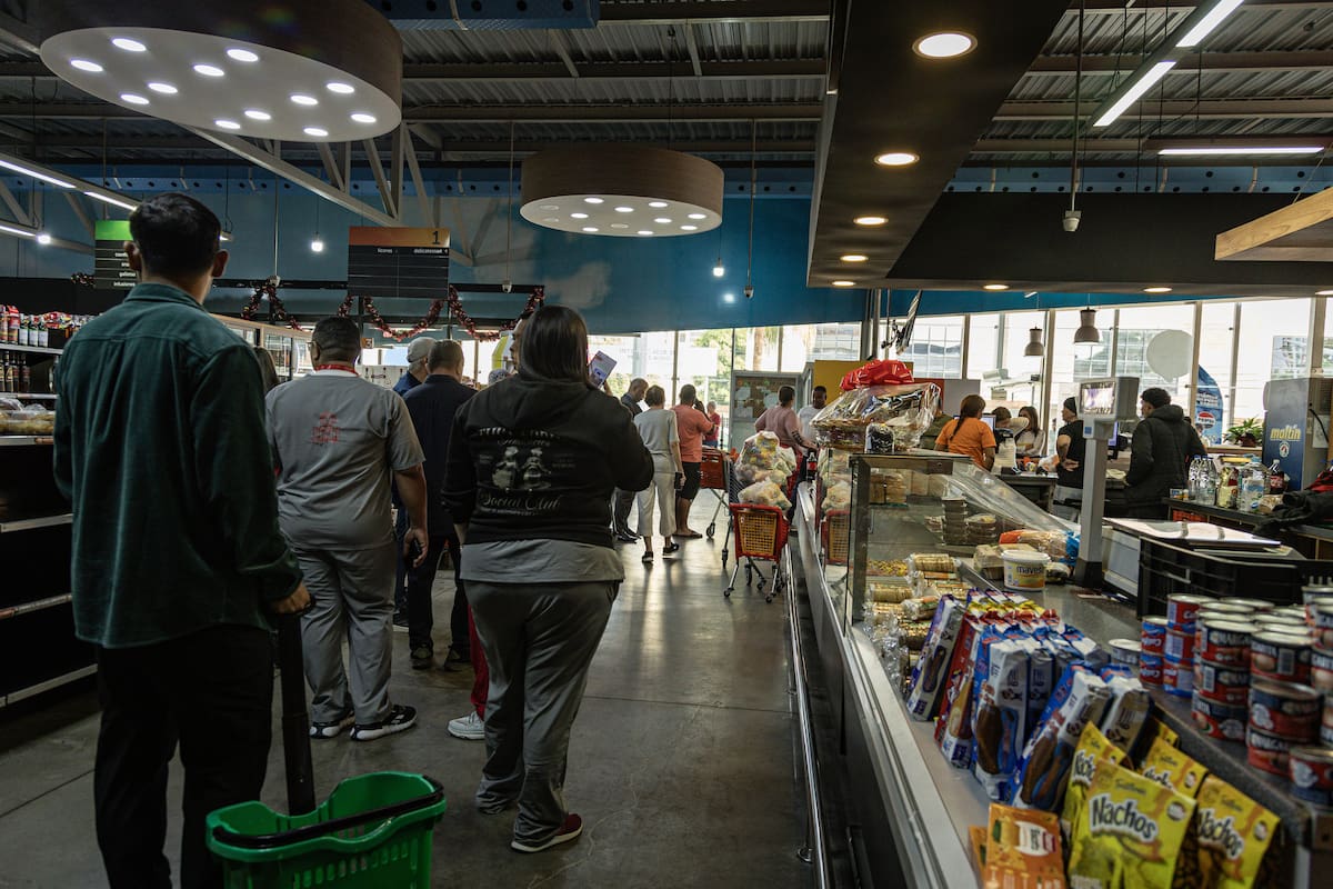 Personas hacen fila en un supermercado para abastecerse este sábado. EFE/ Henry Chirinos