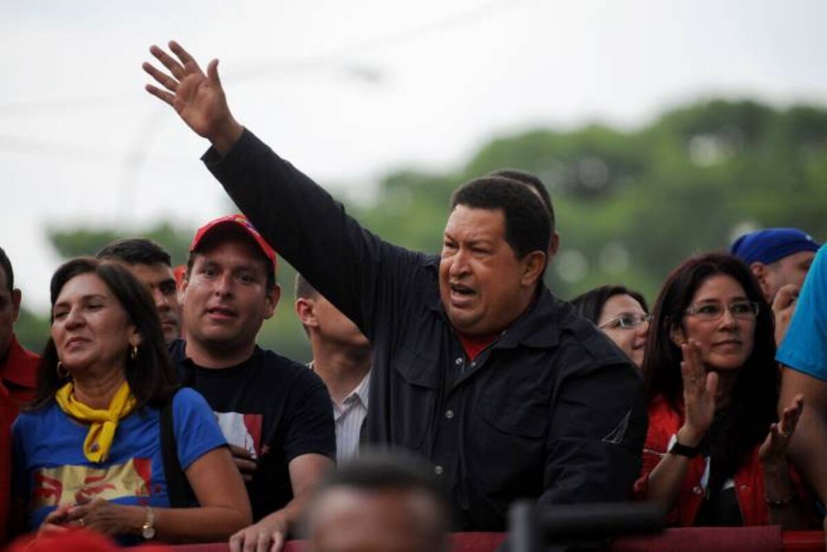Vestido de franela roja y chaqueta azul, el mandatario Hugo Chávez sube a un camión descapotado mientras miles de sus simpatizantes lo saludan. AFP LEO RAMIREZ